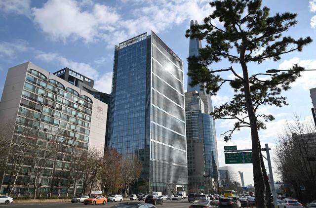 A general view shows the logo of South Korean online delivery service Coupang, at a building (C) housing the company's headquarters in Seoul on December 9, 2025. South Korean police raided the Seoul headquarters of e-commerce giant Coupang on December 9, over a recent data leak believed to have affected almost two-thirds of the country's population. (Photo by Jung Yeon-je / AFP)