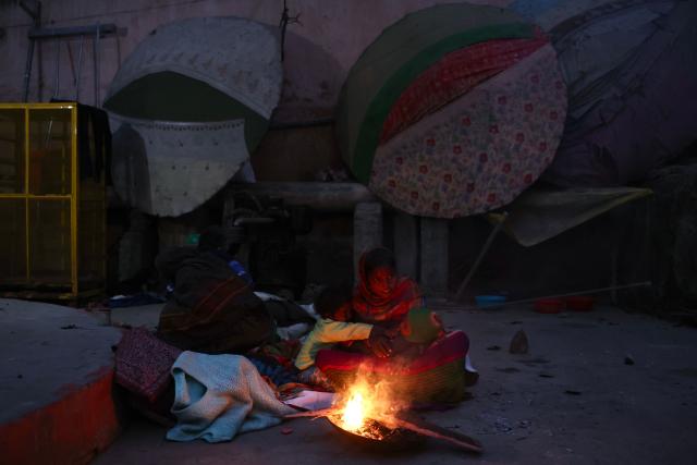 Homeless people keep themselves warm around a bonfire along a street in Varanasi on December 9, 2025. (Photo by Niharika KULKARNI / AFP)