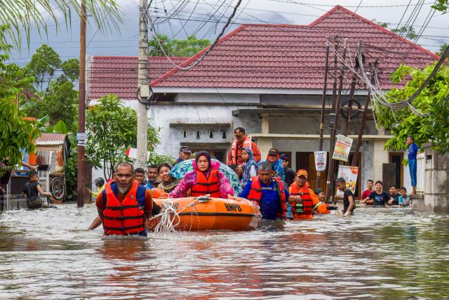 A rescue team evacuates women and children in a rubber boat as floodwaters hit a residential area in Padang, West Sumatra on November 25, 2025. Tropical storms and monsoon rains have pummelled Southeast and South Asia this month, triggering landslides and flash floods from the rainforests of Indonesia's western Sumatra island to highland plantations in Sri Lanka. (Photo by Ade Yuandha / AFP)