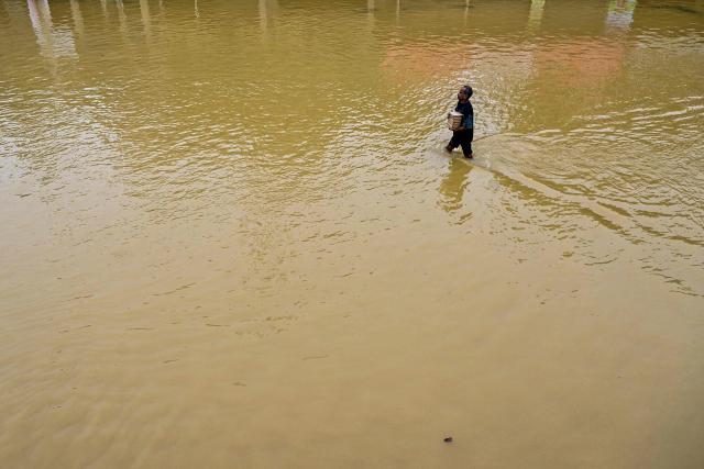 A man wades through a flooded road after heavy rainfall in Kaduwela on the outskirts of Colombo on November 29, 2025. Tropical storms and monsoon rains have pummelled Southeast and South Asia this month, triggering landslides and flash floods from the rainforests of Indonesia's western Sumatra island to highland plantations in Sri Lanka. (Photo by Ishara S. KODIKARA / AFP)