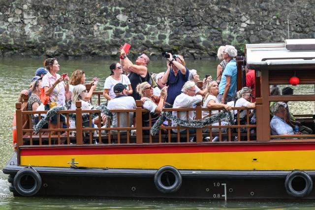 Tourists ride a tour boat along the river in Singapore on December 9, 2025. (Photo by Roslan RAHMAN / AFP)