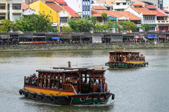 Tourists ride tour boats along the boat quay in Singapore on December 9, 2025. (Photo by Roslan RAHMAN / AFP)