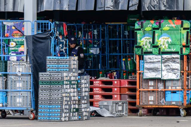 A worker sorts through reusable delivery bags of South Korean e-commerce giant Coupang in Seoul on December 9, 2025. South Korean police raided the Seoul headquarters of e-commerce giant Coupang on December 9, over a recent data leak believed to have affected almost two-thirds of the country's population. (Photo by ANTHONY WALLACE / AFP)