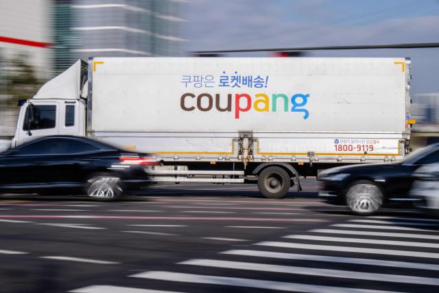 A delivery truck of South Korean e-commerce giant Coupang is driven along a road in Seoul on December 9, 2025. South Korean police raided the Seoul headquarters of e-commerce giant Coupang on December 9, over a recent data leak believed to have affected almost two-thirds of the country's population. (Photo by ANTHONY WALLACE / AFP)