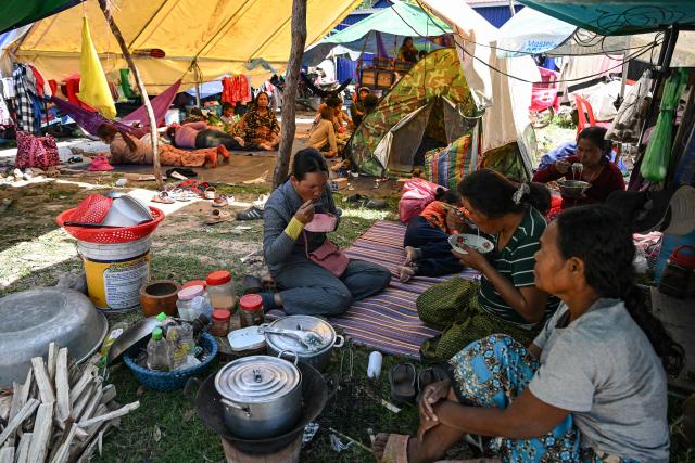 Residents have lunch outside a temple after they evacuated following clashes along the Cambodia-Thailand border, in Siem Reap province on December 9, 2025. Two more Thai soldiers were killed on December 9, in renewed border clashes with neighbour Cambodia, the Thai army said, raising the death toll for Thai troops to three. (Photo by TANG CHHIN SOTHY / AFP)