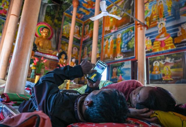 Residents rest inside a temple after they evacuated following clashes along the Cambodia-Thailand border, in Siem Reap province on December 9, 2025. Two more Thai soldiers were killed on December 9, in renewed border clashes with neighbour Cambodia, the Thai army said, raising the death toll for Thai troops to three. (Photo by TANG CHHIN SOTHY / AFP)