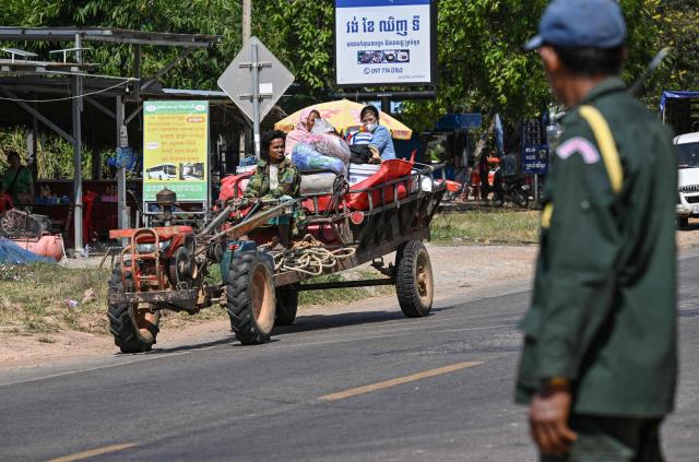 A policeman (R) stands as residents evacuate following clashes along the Cambodia-Thailand border in Siem Reap province on December 9, 2025. Two more Thai soldiers were killed on December 9, in renewed border clashes with neighbour Cambodia, the Thai army said, raising the death toll for Thai troops to three. (Photo by TANG CHHIN SOTHY / AFP)