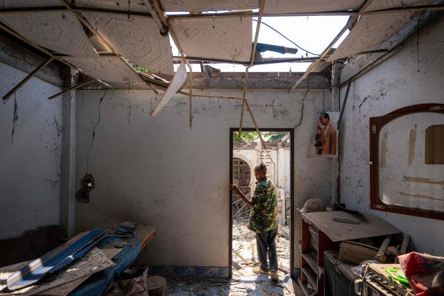 A resident shows part of a house, believed to have been damaged by Cambodian artillery shells during clashes, along the Thai-Cambodia border in Thailand's Sa Kaeo Province on December 9, 2025. The Thai army said on December 9 that Cambodian shells had fallen on two civilian homes in Sa Kaeo province, with no casualties reported. (Photo by Arnun Chonmahatrakool / THAI NEWS PIX / AFP)