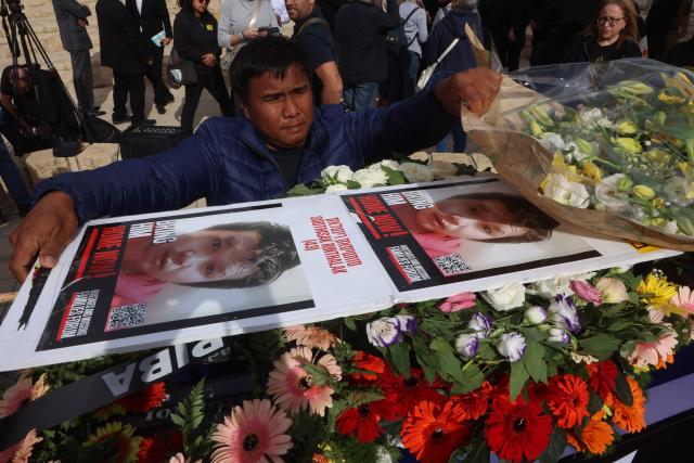 A member of the Thai community in Israel lay a wreath on the coffin of a Thai national Sudthisak Rinthalak, who was kidnapped by Hamas militants from orchards near Kibbutz Be’eri on October 7, 2023, during a ceremony after his body was returned to Israel at Ben-Gurion Airport on December 9, 2025. (Photo by GIL COHEN-MAGEN / AFP)