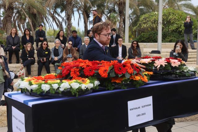 A man stands next to the coffin of a Thai national Sudthisak Rinthalak, who was kidnapped by Hamas militants from orchards near Kibbutz Be’eri on October 7, 2023, during a ceremony after his body was returned to Israel at Ben-Gurion Airport on December 9, 2025. (Photo by GIL COHEN-MAGEN / AFP)