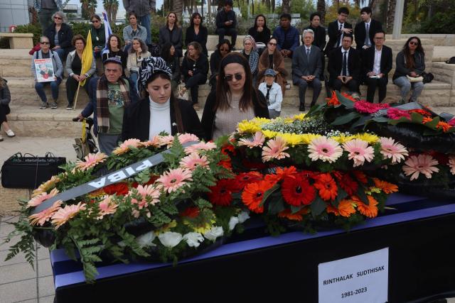 People stand next to the coffin of a Thai national Sudthisak Rinthalak, who was kidnapped by Hamas militants from orchards near Kibbutz Be’eri on October 7, 2023, during a ceremony after his body was returned to Israel at Ben-Gurion Airport on December 9, 2025. (Photo by GIL COHEN-MAGEN / AFP)