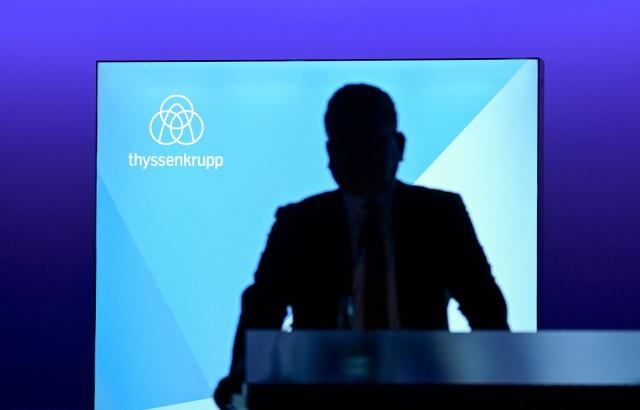 Thyssenkrupp CEO Miguel Angel Lopez Borrego silhouettes against a wall with his company's logo as he arrive to address the annual news conference of German industrial titan Thyssenkrupp at the company's headquarters in Essen, western Germany on December 9, 2025. The company announced it expected a loss next year as it grapples with a tough market environment and seeks to offload employees. The firm said it would lose between 400 and 800 million euros ($466 and $932 million) in 2026 because of weak demand and "in particular" the costs of restructuring its steel business. (Photo by Ina FASSBENDER / AFP)
