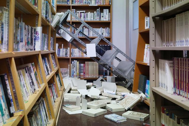 Collapsed bookshelves at a high school library is seen in Hachinohe City in Aomori Prefecture on December 9, 2025, following a 7.5 magnitude earthquake off northern Japan. A big quake off northern Japan left at least 30 injured, authorities said on December 9, damaging roads and leaving thousands without power in freezing temperatures. (Photo by JIJI Press / AFP) / Japan OUT