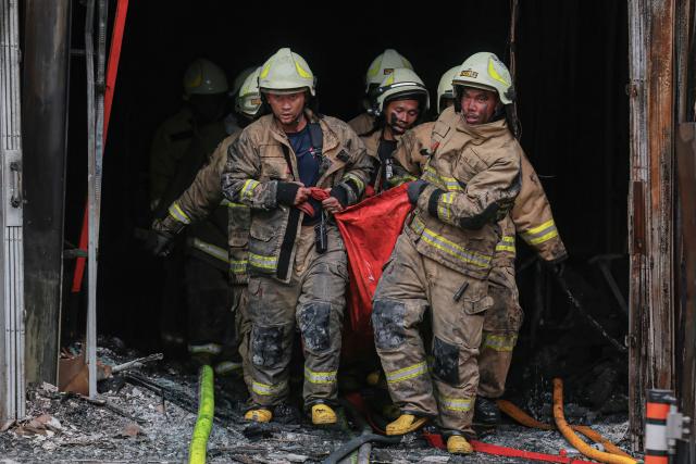 Firefighters move out the body of a victim from a seven-storey building in central Jakarta on December 9, 2025, after a fire that killed at least 20 people. (Photo by SYNATRIA RESPATI / AFP)
