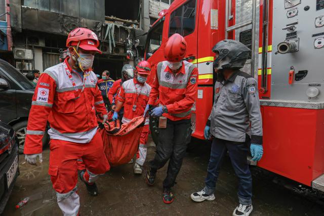 Firefighters move out the body of a victim from a seven-storey building in central Jakarta on December 9, 2025, after a fire that killed at least 20 people. (Photo by SYNATRIA RESPATI / AFP)