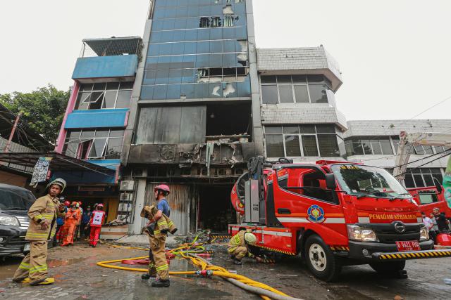 Firefighters are seen at the scene where they have extinguished a fire that killed at least 20 people at a seven-storey building in central Jakarta on December 9, 2025. (Photo by SYNATRIA RESPATI / AFP)