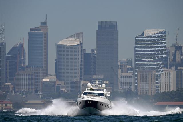 A boat leaves harbour as smoke from bushfires burning on Sydney's outskirts hangs over Sydney Harbour on December 9, 2025. Dozens of bushfires burned along Australia's eastern seaboard on December 6, destroying several houses as a blistering heatwave set in. (Photo by SAEED KHAN / AFP)