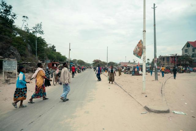 Commuters walk along a road in Uvira on December 9, 2025. Intense fighting is taking place on Tuesday in the eastern Democratic Republic of Congo (DRC), with the M23 group, supported by the Rwandan army, continuing its rapid advance towards Uvira, a strategic Congolese city located near the border with neighboring Burundi and now under threat. The anti-government armed group and the Rwandan soldiers—estimated at 6,000 to 7,000 on Congolese soil according to UN experts—were reportedly only about fifteen kilometers north of the city, home to several hundred thousand inhabitants, as of Tuesday morning, according to security and military sources cited by AFP. (Photo by AFP)