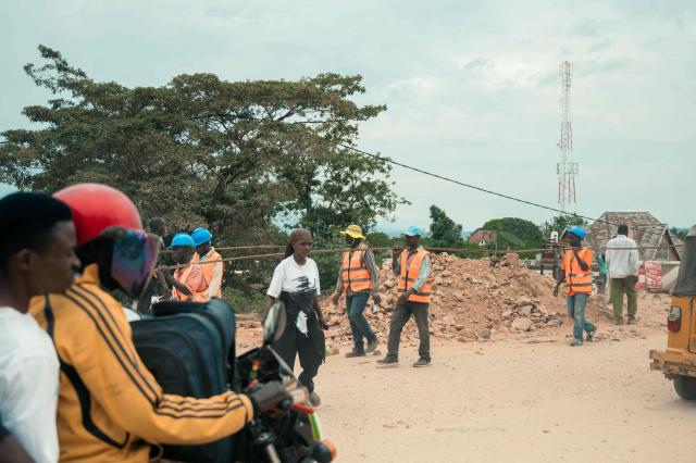 A commuter rides on the back of a motorbike as pedestrians walk along a road in Uvira on December 9, 2025. Intense fighting is taking place on Tuesday in the eastern Democratic Republic of Congo (DRC), with the M23 group, supported by the Rwandan army, continuing its rapid advance towards Uvira, a strategic Congolese city located near the border with neighboring Burundi and now under threat. The anti-government armed group and the Rwandan soldiers—estimated at 6,000 to 7,000 on Congolese soil according to UN experts—were reportedly only about fifteen kilometers north of the city, home to several hundred thousand inhabitants, as of Tuesday morning, according to security and military sources cited by AFP. (Photo by AFP)