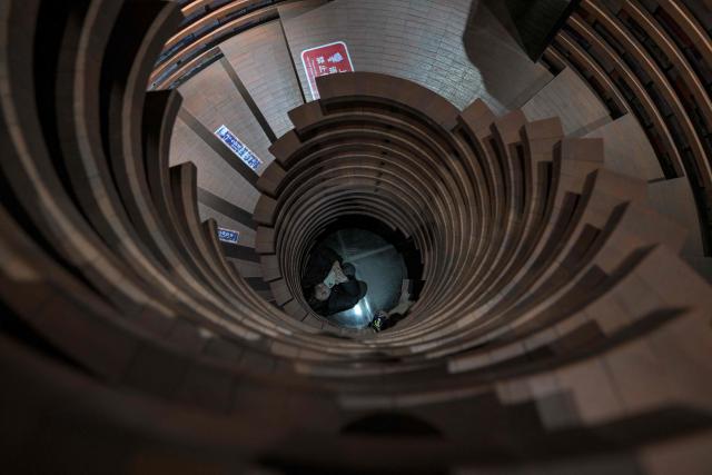 A woman takes pictures of a spiral staircase at a bookstore in Tianjin on December 9, 2025. (Photo by ADEK BERRY / AFP)