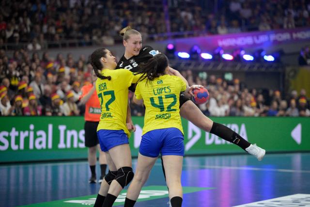 Germany's right back #77 Viola Leuchter (C) vies for the ball with Brazil's left back #77 Kelly De Abreu Rosa (L) and Brazil's centre back #42 Jhennifer Dos Santos (R) during the quarter final match between Germany and Brazil of the IHF Women's Handball World Championship in Dortmund, western Germany on December 9, 2025. (Photo by Sascha Schuermann / AFP)