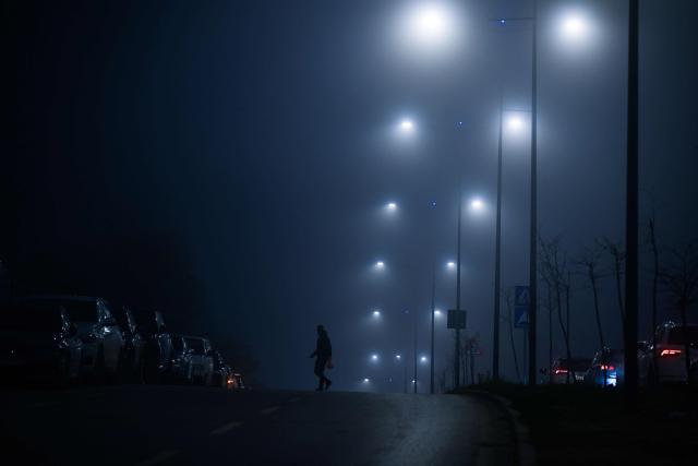 A pedestrian crosses a road under heavy smog in Pristina on December 9, 2025. (Photo by Armend NIMANI / AFP)