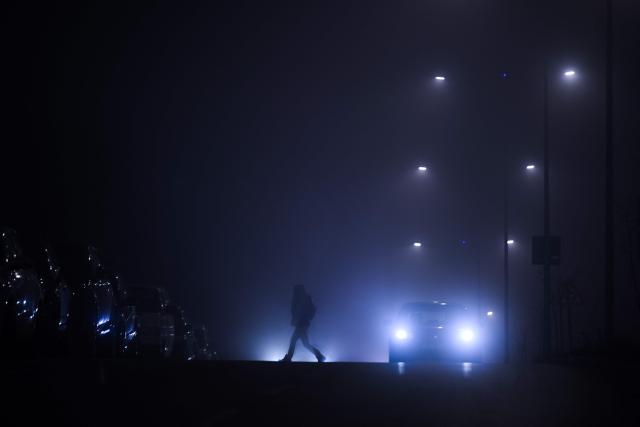 A pedestrian crosses a road in heavy smog in Pristina on December 9, 2025. (Photo by Armend NIMANI / AFP)