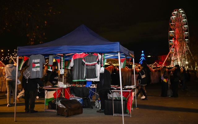This photograph shows a view of a goods selling stand with Palestinian flags ahead of a charity concert "Together for Palestine", with the La Villette Christmas market in the background in Paris on December 9, 2025. (Photo by Anna KURTH / AFP)
