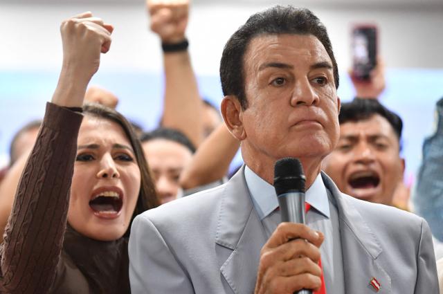 Salvador Nasralla, presidential candidate for the opposition Liberal Party, speaks during a press conference next to his wife Iroshka Elvir in Tegucigalpa on December 9, 2025. Nasralla made allegations of electoral corruption on December 9, 2025, after a stalled ballot count in the November 30 general election. (Photo by Orlando SIERRA / AFP)