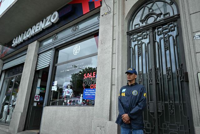 A Federal Police officer stands guard outside the offices of the Club San Lorenzo football team during a raid in Buenos Aires on December 9, 2025. Argentine authorities raided the headquarters of the national football association and several major teams on Tuesday as part of a money-laundering probe, a police source told AFP. (Photo by Luis ROBAYO / AFP)