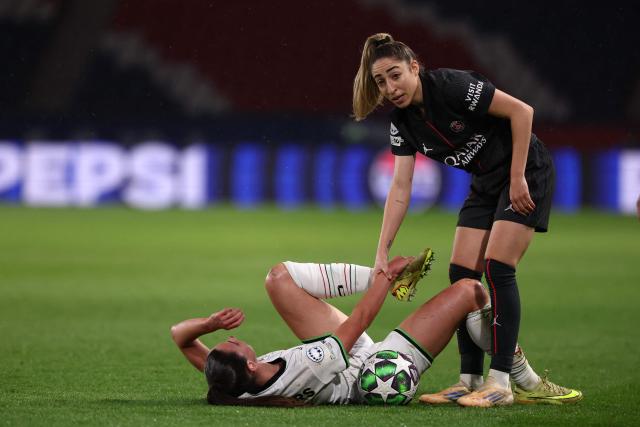 Paris Saint-Germain's Spanish defender #77 Olga Carmona (R) helps OH Louvain's Belgian forward #10 Aurelie Reynders (C) to get back up during the UEFA Women's Champions League first round day five football match between Paris Saint-Germain and OH Louvain at the Parc des Princes in Paris on December 9, 2025. (Photo by FRANCK FIFE / AFP)