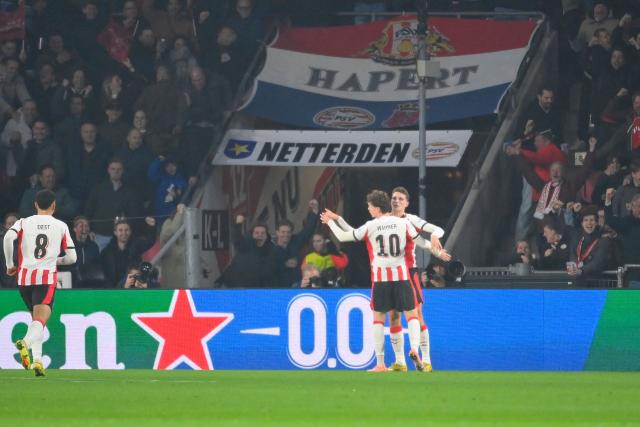 PSV Eindhoven's Dutch midfielder #20 Guus Til (R) celebrates scoring his team's first goal with teammates during the UEFA Champions League, league phase day 6, football match between PSV Eindhoven (NED) and Atletico Madrid (ESP), at the Philips Stadion, in Eindhoven, south of The Netherlands, on December 9, 2025. (Photo by JOHN THYS / AFP)
