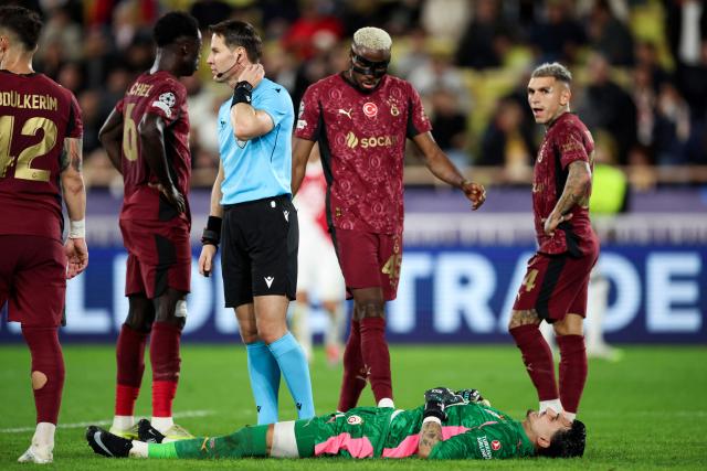 Galatasaray's Nigerian forward #45 Victor Osimhen (rear C) checks on Galatasaray's Turkish goalkeeper #01 Ugurcan Cakir (down) lying on the ground following an injury during the UEFA Champions League, league phase, football match between Monaco and Galatasaray, at the Stade Louis II stadium, in Monaco, on December 9, 2025. (Photo by Valery HACHE / AFP)