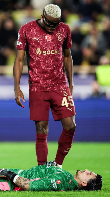 Galatasaray's Nigerian forward #45 Victor Osimhen (rear C) checks on Galatasaray's Turkish goalkeeper #01 Ugurcan Cakir (down) lying on the ground following an injury during the UEFA Champions League, league phase, football match between Monaco and Galatasaray, at the Stade Louis II stadium, in Monaco, on December 9, 2025. (Photo by Valery HACHE / AFP)