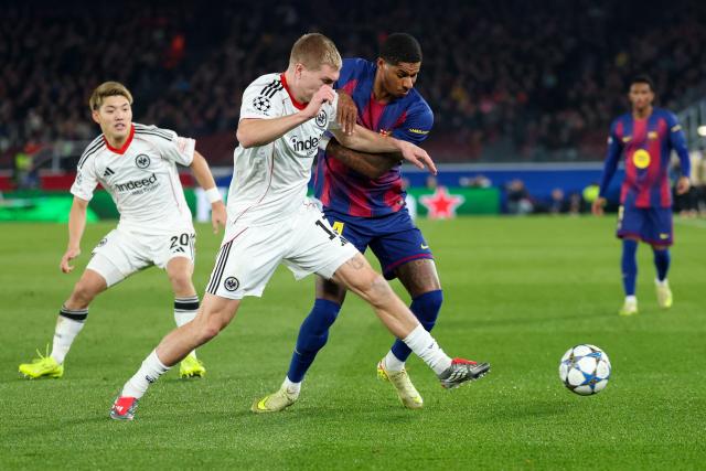 Barcelona's English forward #14 Marcus Rashford (C) and Frankfurt's Danish defender #13 Rasmus Kristensen vie for the ball during the UEFA Champions League league phase day 6 football match between FC Barcelona and Eintracht Frankfurt at Camp Nou Stadium in Barcelona on December 9, 2025. (Photo by Lluis GENE / AFP)