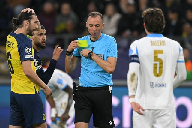 Portuguese referee Joao Pinheiro issues Union St-Gilloise's Algerian midfielder #08 Adem Zorgane a yellow card during the UEFA Champions League, league phase day 6, football match between Royale Union Saint-Gilloise (BEL) and Olympique de Marseille (FRA), at the RSC Anderlecht Stadium in Brussels, on December 9, 2025. (Photo by NICOLAS TUCAT / AFP)