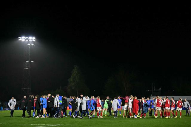 Players and staff shake hands on the pitch after the UEFA Women's Champions League, league phase football match between Arsenal and FC Twente at Meadow Park, in Borehamwood, north of London on December 9, 2025. Arsenal won the game 1-0. (Photo by Ben STANSALL / AFP)