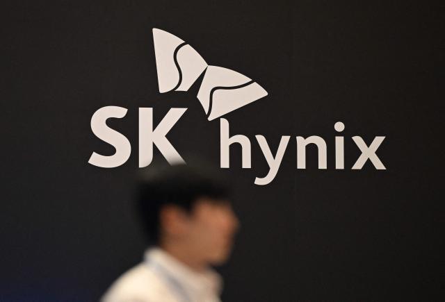 (FILES) In this file photo taken on October 24, 2024, a man walks past the logo of SK hynix during a semiconductor exhibition at the COEX convention and exhibition centre in Seoul. South Korean chip giant SK hynix said on December 10, 2025, it was considering a US stock market listing using its treasury shares as part of efforts to boost shareholder value. (Photo by JUNG YEON-JE / AFP)