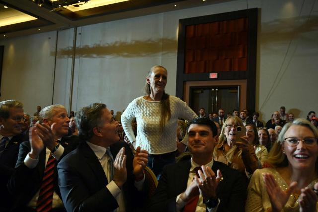 Donna Zajack (C), an attendee who was called to join him on the stage by US President Donald Trump, stands up as he delivers remarks on the economy at Mount Airy Casino Resort in Mount Pocono, Pennsylvania, on December 9, 2025. (Photo by ANDREW CABALLERO-REYNOLDS / AFP)