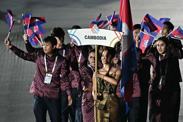 Members of Cambodia's delegation wave their country's national flag as they take part in the athletes' parade during the opening ceremony of the 33rd Southeast Asian Games (SEA Games) at Rajamangala National Stadium in Bangkok on December 9, 2025. Cambodia withdraws from SEA Games in Thailand, organisers announced on December 10, 2025. (Photo by Lillian SUWANRUMPHA / AFP)