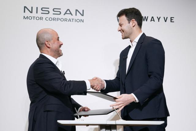 Nissan Motor CEO Ivan Espinosa (L) and Wayve Technologies CEO Alex Kendall (R) shake hands at a signing ceremony for the collaboration agreement between the two companies regarding technologies for the ProPILOT next-generation driver assistance technology system in Tokyo on December 10, 2025. (Photo by Kazuhiro NOGI / AFP)