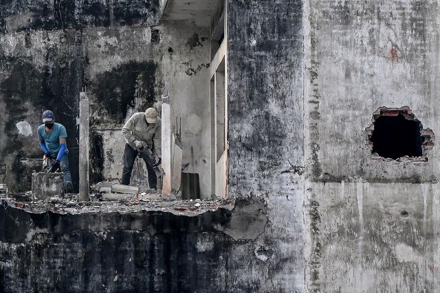 Workers dismantle part of a building at a demolition site in Hanoi on December 10, 2025. (Photo by Nhac NGUYEN / AFP)