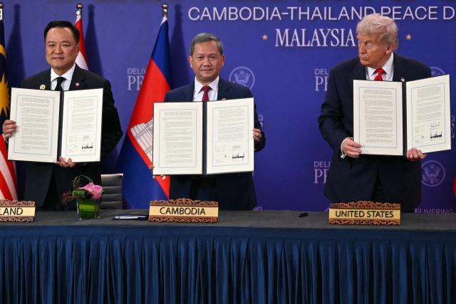 (FILES) US President Donald Trump (R) looks at Cambodia's Prime Minister Hun Manet (C) and Thailand's Prime Minister Anutin Charnvirakul as they take part in the ceremonial signing of a ceasefire agreement on the sidelines of the 47th Association of Southeast Asian Nations (ASEAN) Summit in Kuala Lumpur on October 26, 2025. Half a million evacuees in Cambodia and Thailand were sheltering in pagodas, schools and other safe havens on December 10, 2025 after fleeing renewed fighting in a century-old border dispute in which US President Donald Trump has vowed to again intercede. (Photo by ANDREW CABALLERO-REYNOLDS / AFP)