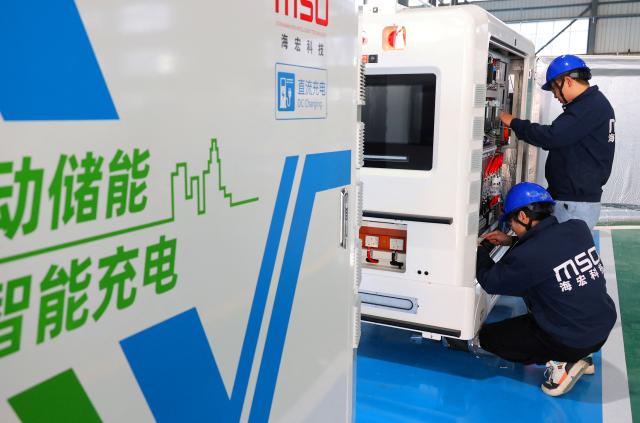 Workers install a smart charging robot for mobile energy storage at a factory in Lianyungang, eastern China's Jiangsu province on December 10, 2025. (Photo by AFP) / China OUT