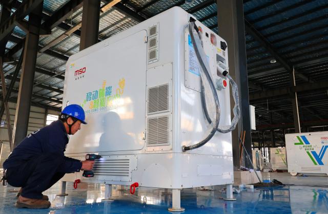 A worker installs a smart charging robot for mobile energy storage at a factory in Lianyungang, eastern China's Jiangsu province on December 10, 2025. (Photo by AFP) / China OUT