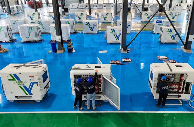 Workers install smart charging robots for mobile energy storage at a factory in Lianyungang, eastern China's Jiangsu province on December 10, 2025. (Photo by AFP) / China OUT
