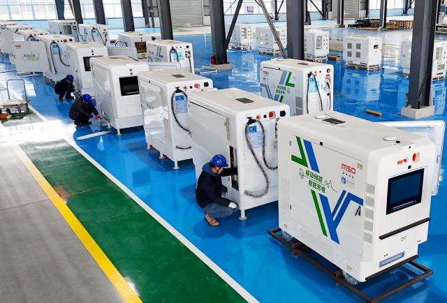 Workers install smart charging robots for mobile energy storage at a factory in Lianyungang, eastern China's Jiangsu province on December 10, 2025. (Photo by AFP) / China OUT