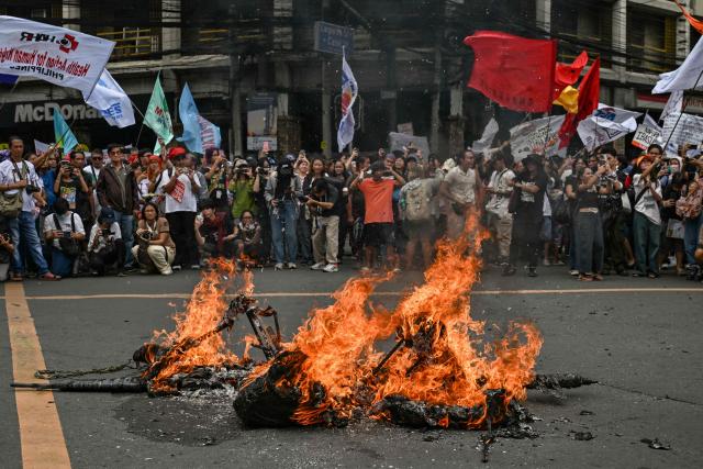 People burn an effigy of Philippines' Vice President Sara Duterte and Philippines' President Ferdinand Marcos Jr. during a protest held to mark the International Human Rights Day in Manila on December 10, 2025. (Photo by Jam STA ROSA / AFP)