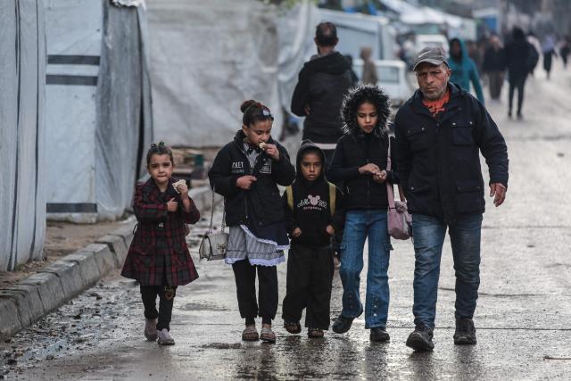 A man takes his children to school in Deir al-Balah, in the central Gaza Strip, on December 10, 2025. Hamas said on December 9 that the Gaza ceasefire plan cannot proceed to its second phase as long as Israeli "violations" persist and called on mediators to pressure Israel to respect the agreement. The US-sponsored ceasefire, in effect since October 10, halted the war that began after Hamas's deadly attack on Israel on October 7, 2023. But it remains fragile as Israel and Hamas accuse each other almost daily of breaches. (Photo by BASHAR TALEB / AFP)