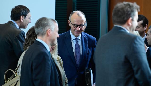 German Chancellor Friedrich Merz (C) greets his cabinet colleagues as he arrives prior to the start of the weekly meeting of the German cabinet on December 10, 2025 at the Chancellery in Berlin. (Photo by John MACDOUGALL / AFP)